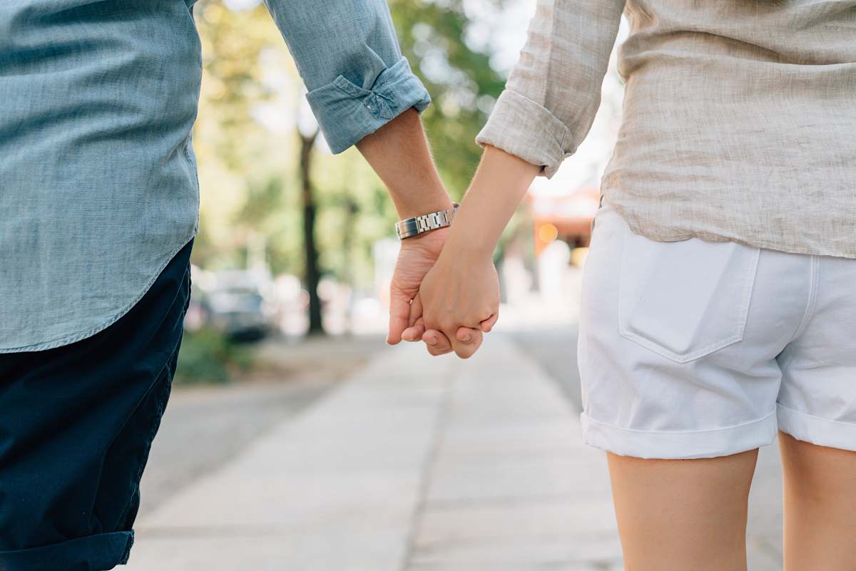 holding hands man and woman holding hands together in walkway during daytime people